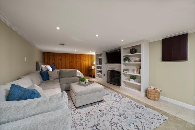 living room featuring crown molding, wood walls, a fireplace, baseboards, and recessed lighting