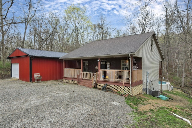 1335 Mingo Rd, Chillicothe, OH 45601 - view of front of property featuring a porch, gravel driveway, an outdoor structure, central AC unit, and a garage
