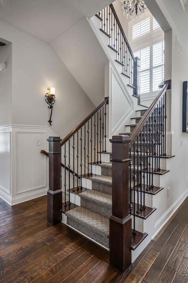 11061 Kingfisher Pl, Plain City, OH 43064 - stairs with hardwood / wood-style floors, a chandelier, visible vents, a decorative wall, and wainscoting