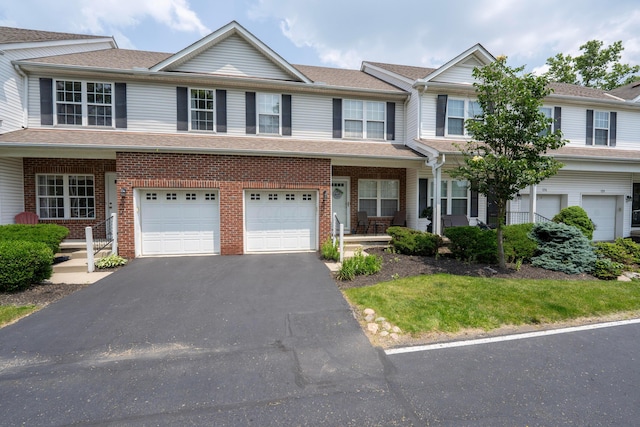 1218 Green Dr Unit 604, Columbus, OH 43230 - view of property with asphalt driveway, an attached garage, a porch, and brick siding