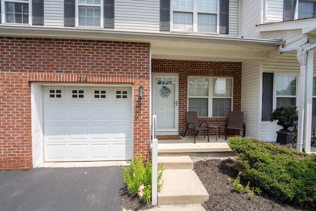 1218 Green Dr Unit 604, Columbus, OH 43230 - view of exterior entry featuring covered porch, brick siding, a garage, and driveway