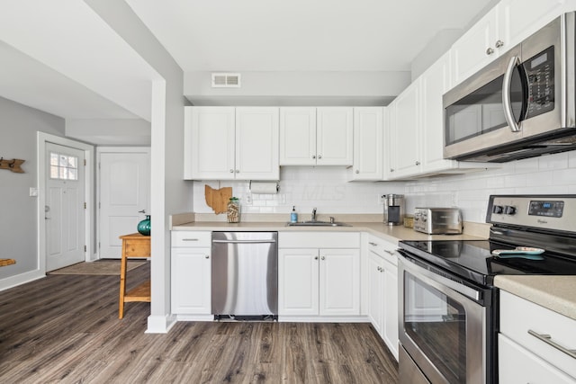 72 Miami Ave, Columbus, OH 43203 - kitchen featuring light countertops, white cabinetry, dark wood finished floors, stainless steel appliances, and visible vents