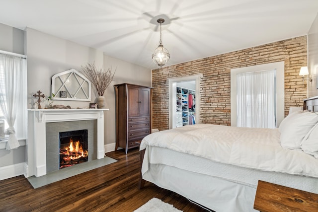 72 Miami Ave, Columbus, OH 43203 - bedroom with a fireplace with flush hearth, a spacious closet, dark wood-style floors, brick wall, and baseboards