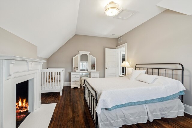 72 Miami Ave, Columbus, OH 43203 - bedroom featuring a lit fireplace, vaulted ceiling, baseboards, visible vents, and dark wood-type flooring