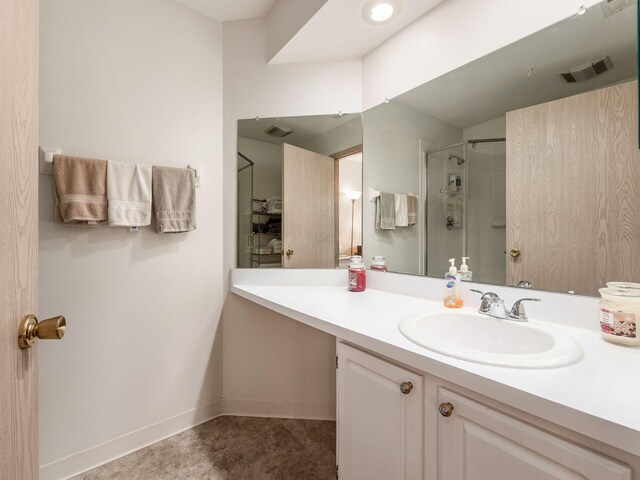 full bathroom with a shower with door, visible vents, baseboards, and vanity