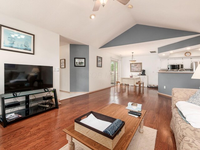 living area featuring ceiling fan, dark wood finished floors, baseboards, and lofted ceiling