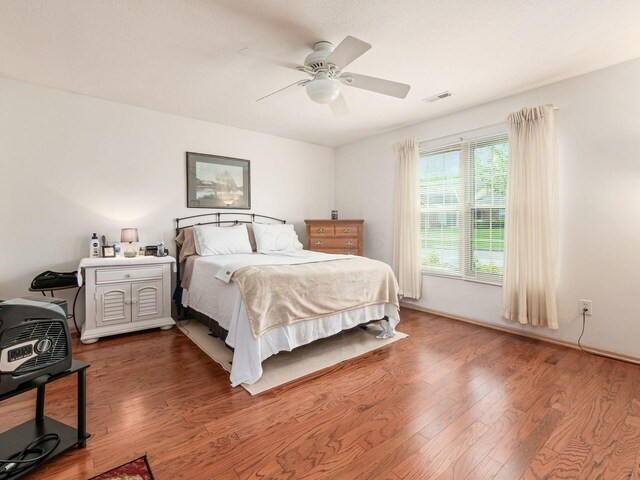 bedroom featuring ceiling fan, visible vents, and wood finished floors