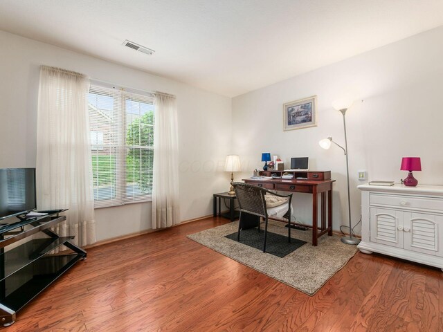 office featuring baseboards, visible vents, and wood finished floors