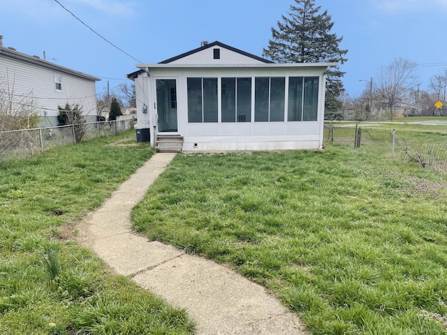 back of house with a yard, a sunroom, a fenced backyard, and entry steps