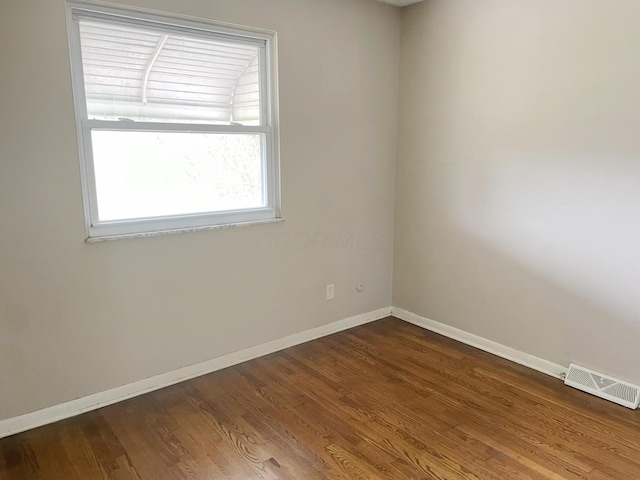 spare room with visible vents, baseboards, and dark wood-style floors