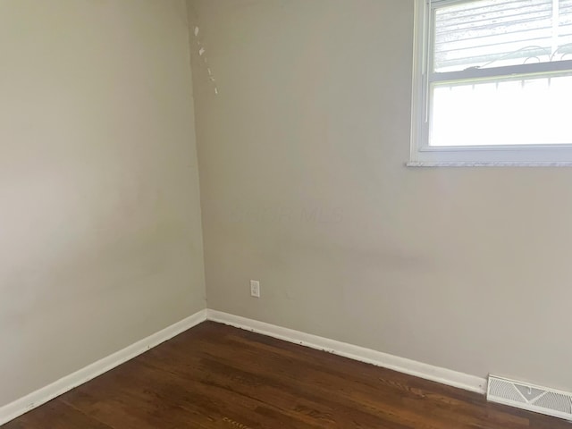 empty room with visible vents, baseboards, and dark wood-style floors