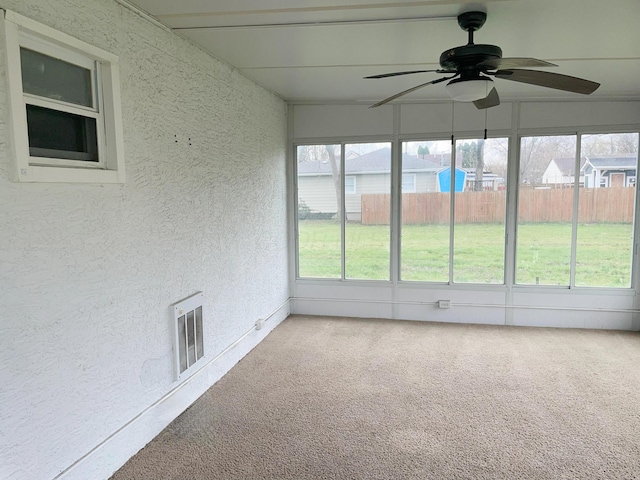 unfurnished sunroom with ceiling fan, visible vents, and plenty of natural light