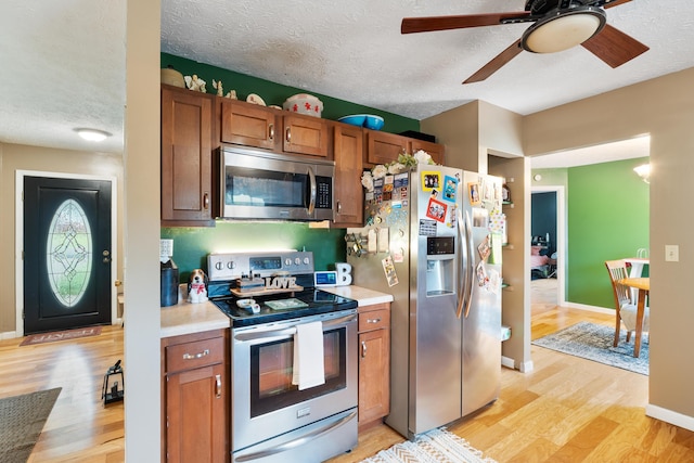 51 Township Rd Unit 1357, South Point, OH 45680 - kitchen with appliances with stainless steel finishes, a textured ceiling, light countertops, light wood-style floors, and brown cabinetry