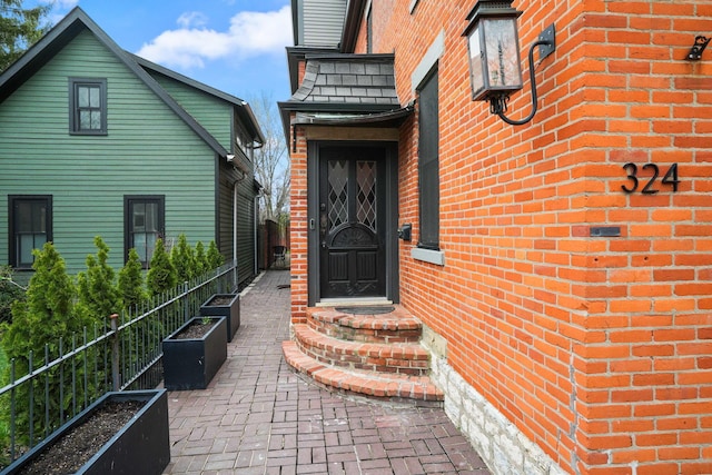 324 Jackson St, Columbus, OH 43206 - property entrance with fence, brick siding, and roof with shingles