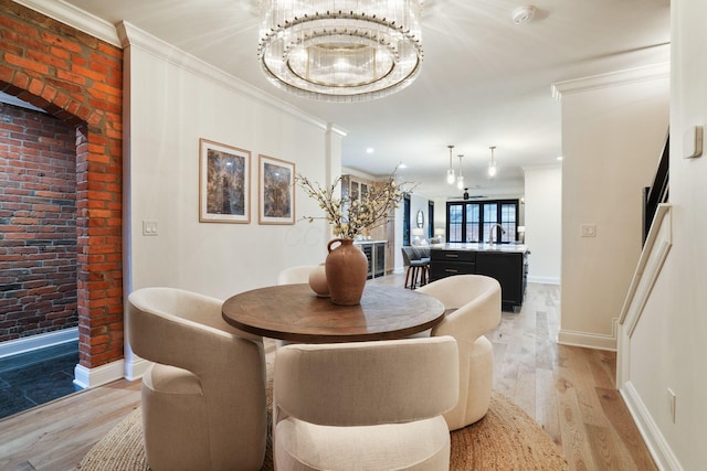 324 Jackson St, Columbus, OH 43206 - dining area with baseboards, ornamental molding, light wood-style floors, brick wall, and an inviting chandelier