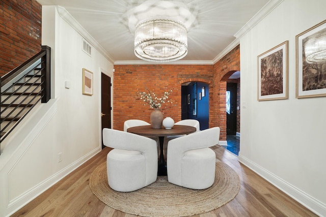 324 Jackson St, Columbus, OH 43206 - dining space with a chandelier, wood finished floors, brick wall, arched walkways, and ornamental molding