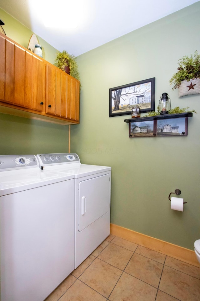 washroom with independent washer and dryer, light tile patterned floors, cabinet space, and baseboards