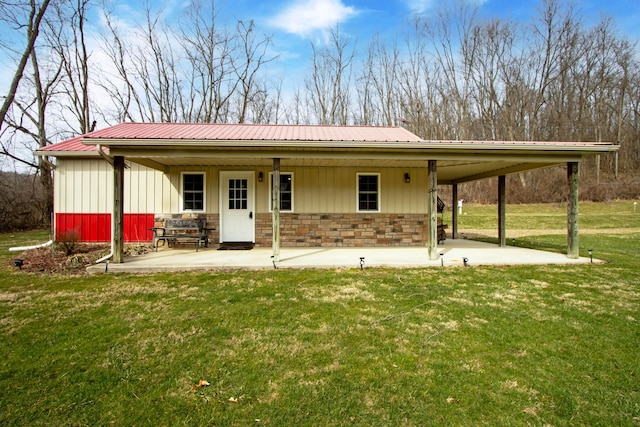 rear view of property with a lawn, metal roof, and a patio