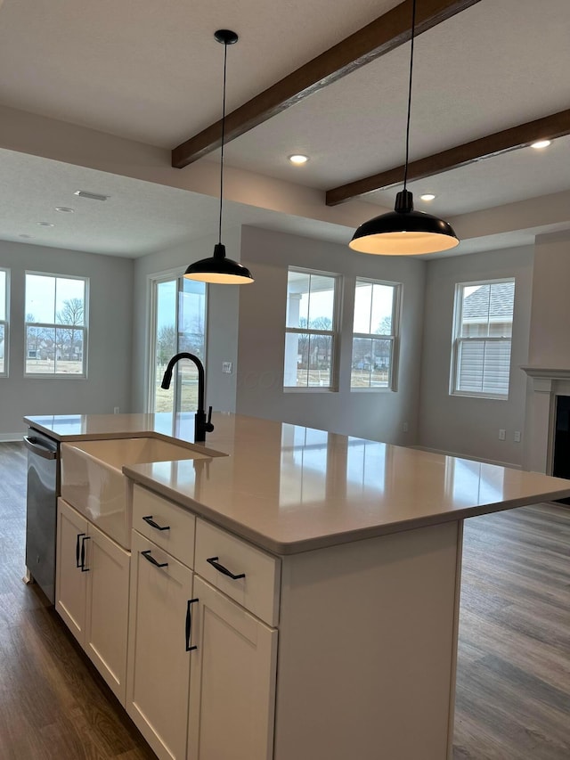 kitchen with open floor plan, dark wood-style floors, beamed ceiling, and stainless steel dishwasher