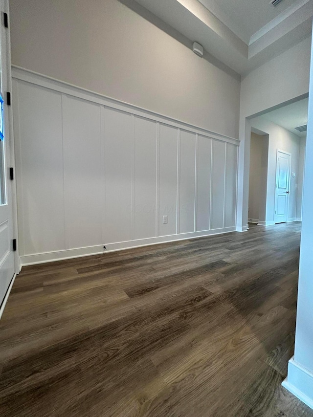 unfurnished room with a decorative wall and dark wood finished floors