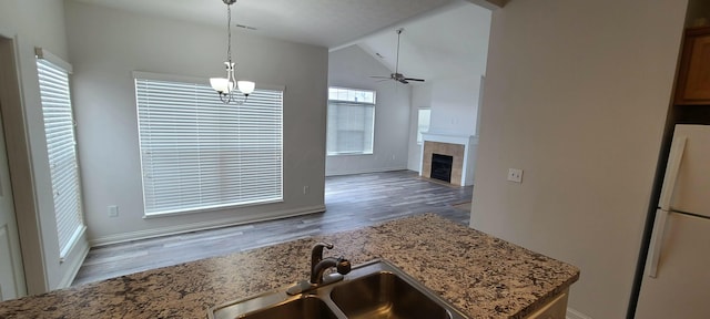 kitchen with wood finished floors, vaulted ceiling, freestanding refrigerator, and a sink