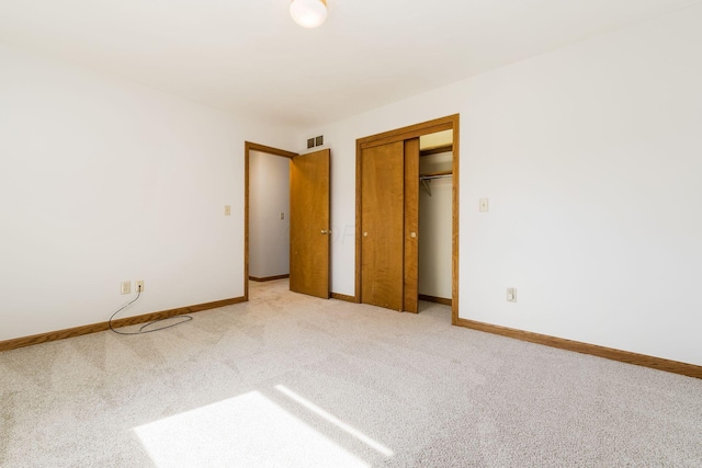 unfurnished bedroom featuring baseboards, visible vents, light carpet, and a closet