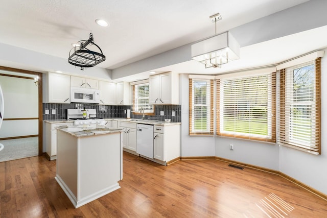 kitchen featuring white cabinets, light wood finished floors, white appliances, baseboards, and tasteful backsplash