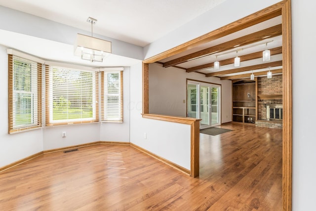 interior space featuring beamed ceiling, baseboards, visible vents, and wood finished floors