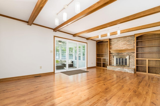 unfurnished living room featuring beamed ceiling, baseboards, and wood finished floors