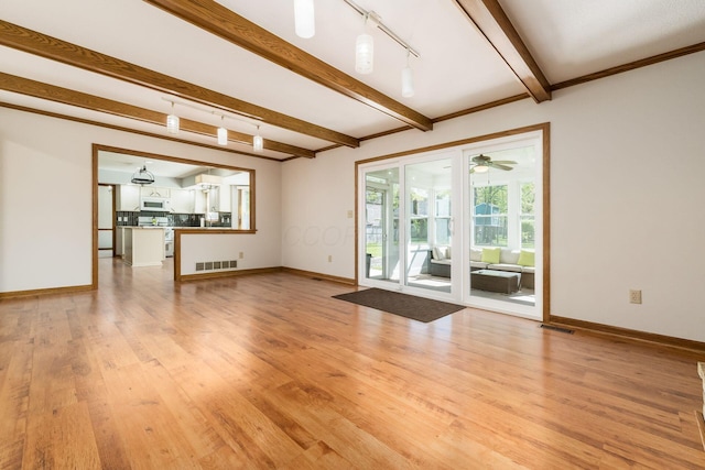 unfurnished living room with beam ceiling, rail lighting, light wood-style flooring, baseboards, and visible vents