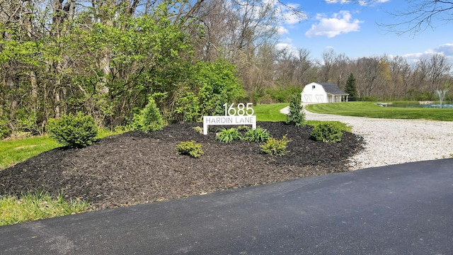 surrounding community featuring driveway, an outdoor structure, a yard, and a water view