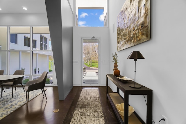 entryway with a wealth of natural light, visible vents, wood finished floors, and a high ceiling