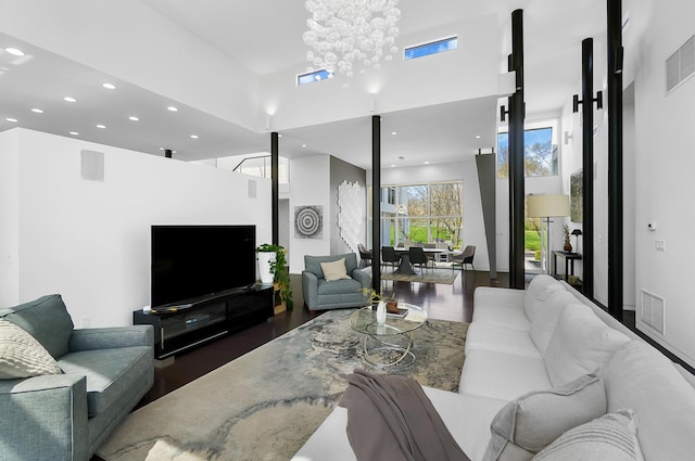 living room with a high ceiling, wood finished floors, visible vents, and recessed lighting