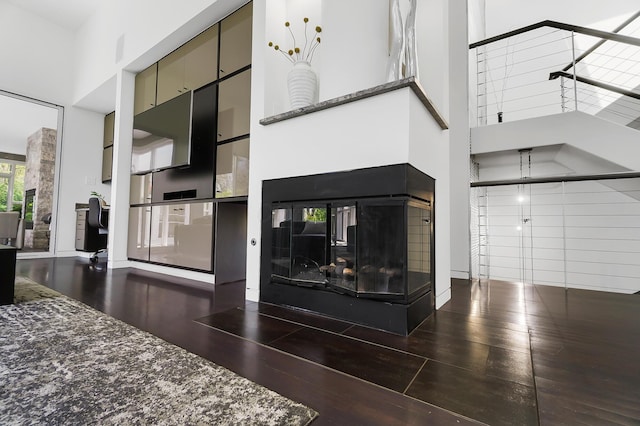 interior space with hardwood / wood-style flooring, a high ceiling, and a multi sided fireplace