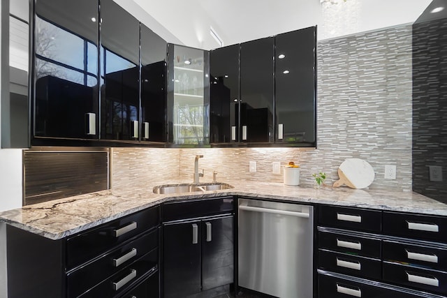 kitchen featuring dishwasher, decorative backsplash, dark cabinetry, and a sink