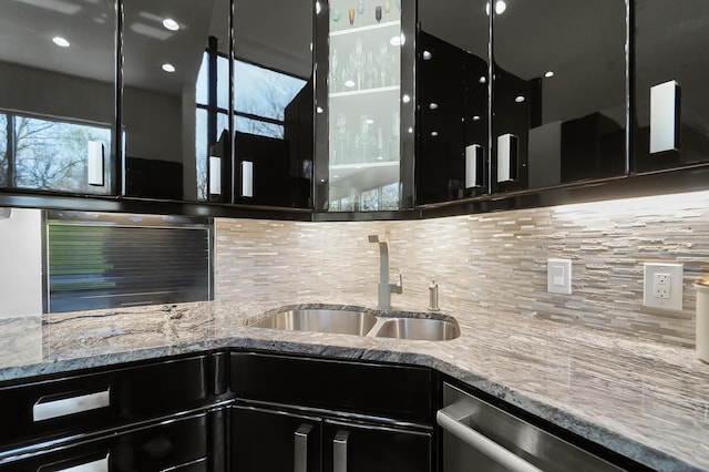 kitchen featuring dishwasher, a wealth of natural light, dark cabinets, and a sink