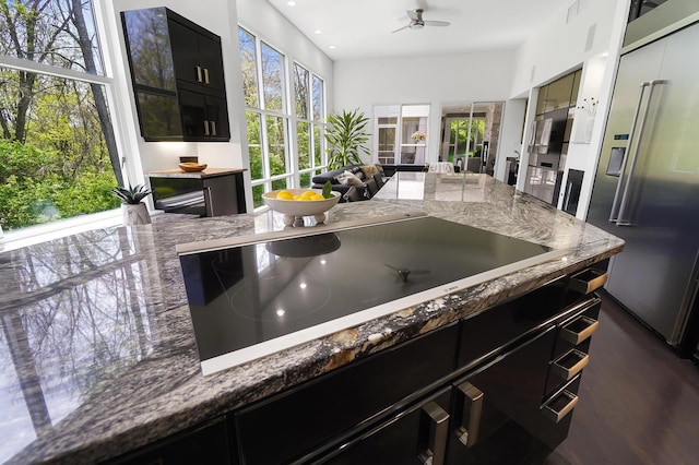 kitchen with black electric cooktop, high quality fridge, open floor plan, dark cabinetry, and ceiling fan