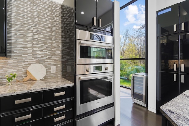 kitchen featuring wine cooler, plenty of natural light, backsplash, dark cabinets, and double oven