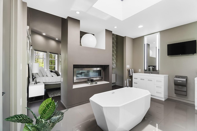 bathroom with recessed lighting, vanity, connected bathroom, a skylight, and a freestanding tub
