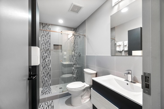 bathroom featuring tile walls, toilet, visible vents, and a stall shower