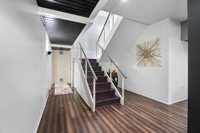 staircase with baseboards, wood finished floors, and visible vents