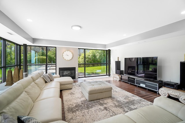 living area with a glass covered fireplace, wood finished floors, and recessed lighting