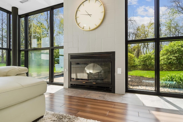 doorway to outside with visible vents, expansive windows, wood finished floors, and a tile fireplace