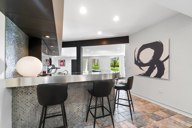 kitchen featuring a peninsula, a kitchen breakfast bar, stone finish floor, and recessed lighting