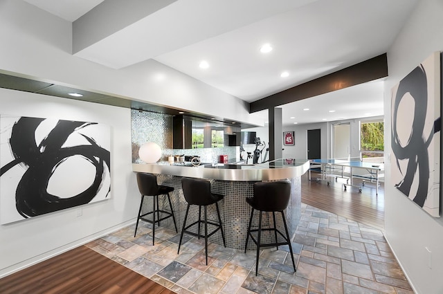 kitchen with stone tile floors, a breakfast bar, recessed lighting, and tasteful backsplash