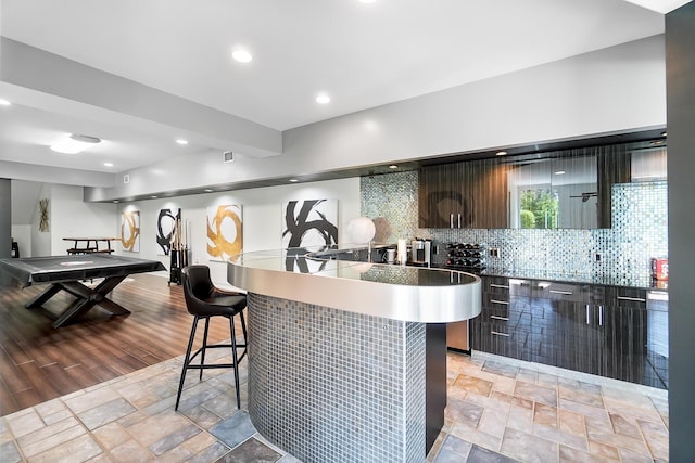 kitchen with modern cabinets, backsplash, stone finish floor, and a kitchen bar