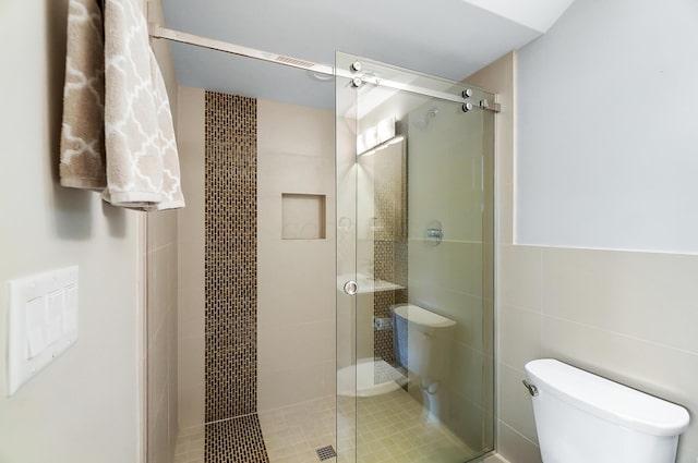 full bath with a shower stall, toilet, and tile walls