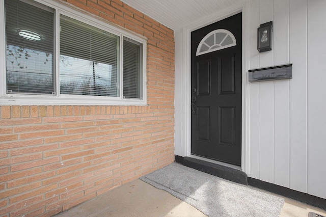 doorway to property featuring board and batten siding and brick siding