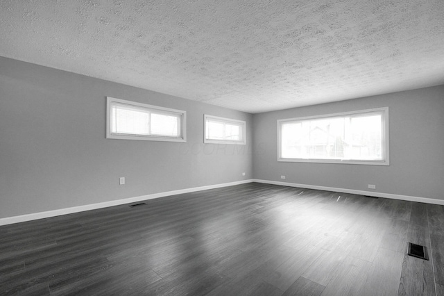 spare room featuring a textured ceiling, dark wood finished floors, and visible vents