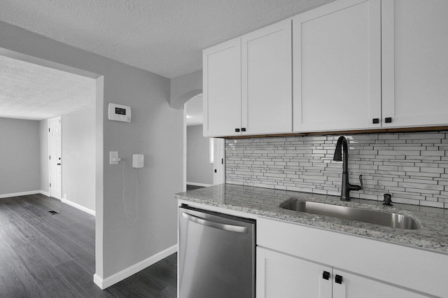 kitchen with stainless steel dishwasher, a textured ceiling, a sink, baseboards, and backsplash